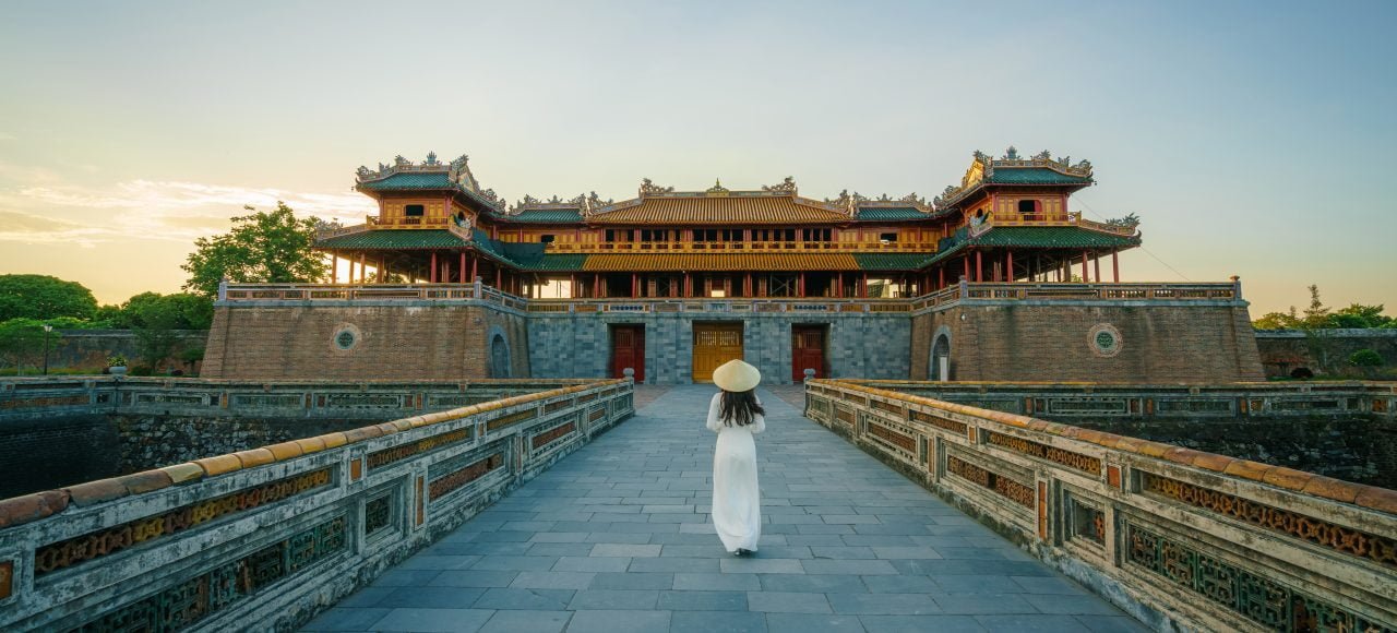 Ngo Mon gate - the main entrance of forbidden Hue Imperial City in Hue city, Vietnam, with Vietnamese girl wearing traditional dress Ao Dai