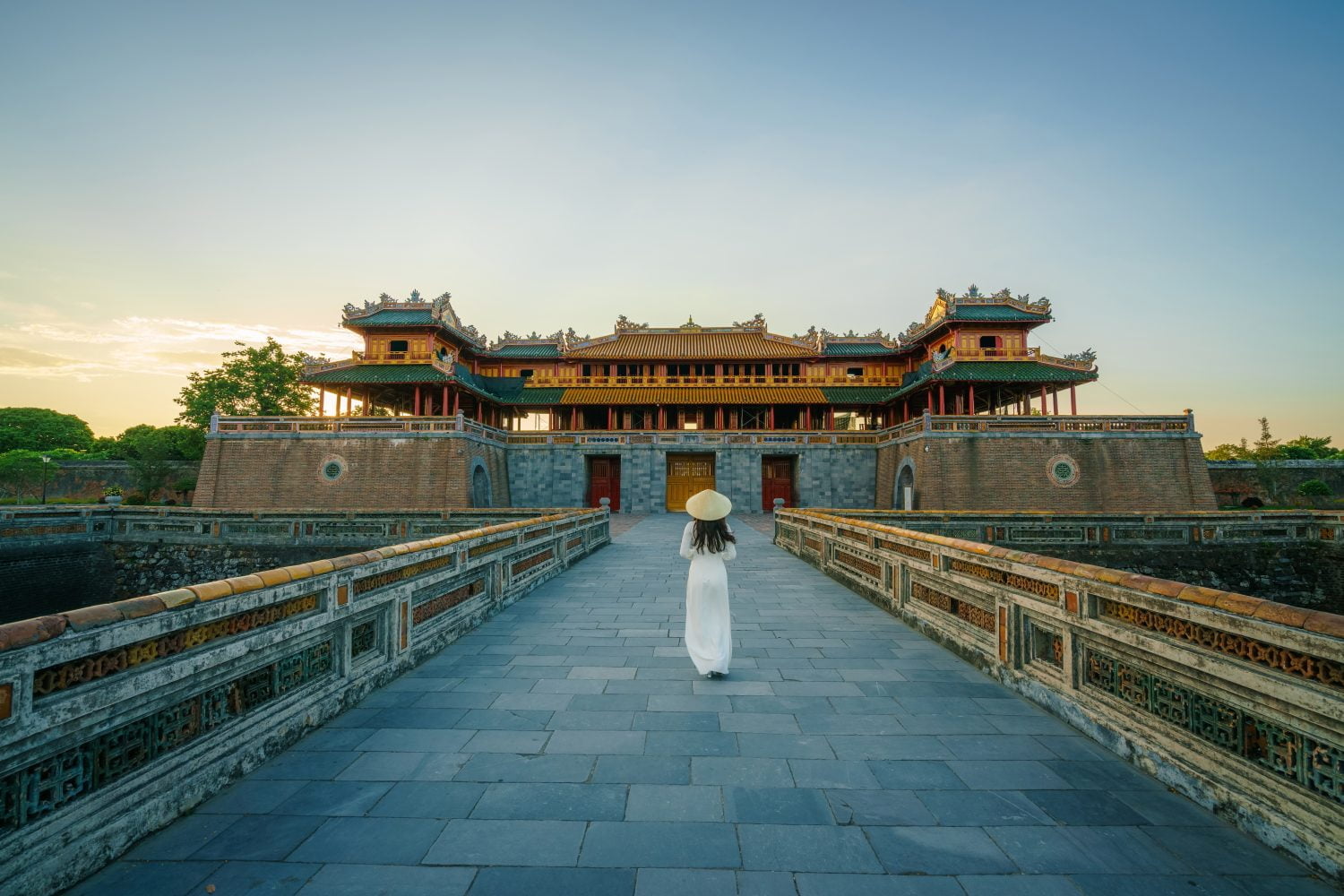 Ngo Mon gate - the main entrance of forbidden Hue Imperial City in Hue city, Vietnam, with Vietnamese girl wearing traditional dress Ao Dai