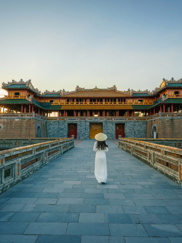 Ngo Mon gate - the main entrance of forbidden Hue Imperial City in Hue city, Vietnam, with Vietnamese girl wearing traditional dress Ao Dai