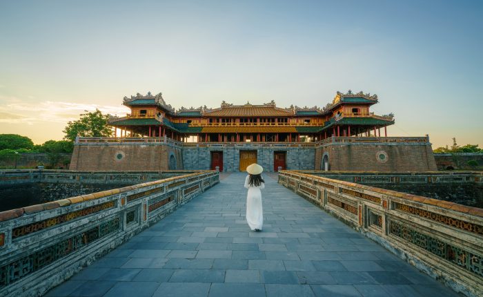Ngo Mon gate - the main entrance of forbidden Hue Imperial City in Hue city, Vietnam, with Vietnamese girl wearing traditional dress Ao Dai
