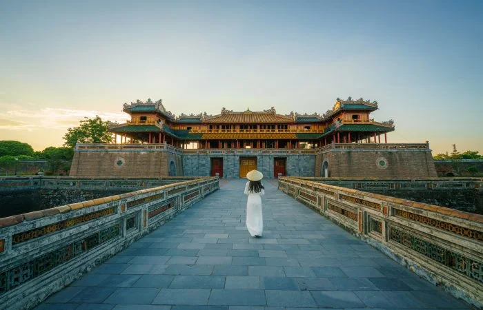 Ngo Mon gate - the main entrance of forbidden Hue Imperial City in Hue city, Vietnam, with Vietnamese girl wearing traditional dress Ao Dai