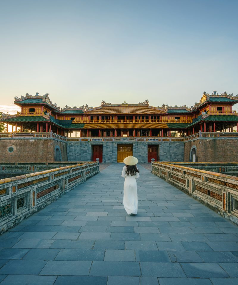 Ngo Mon gate - the main entrance of forbidden Hue Imperial City in Hue city, Vietnam, with Vietnamese girl wearing traditional dress Ao Dai