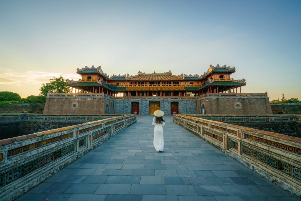 Ngo Mon gate - the main entrance of forbidden Hue Imperial City in Hue city, Vietnam, with Vietnamese girl wearing traditional dress Ao Dai